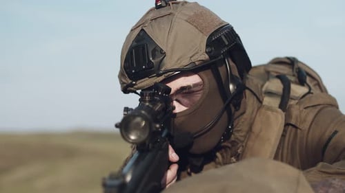 a Soldier with a Sniper Rifle Aims at the Lens and Prepares to Shoot