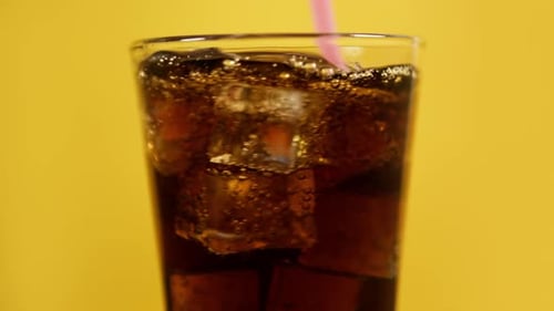 Refreshing Soda with Ice and Straw on Yellow