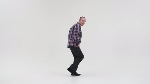 A Man in Dark Trousers, a White T-shirt and a Checkered Shirt Is Dancing a Break Dance with His Legs