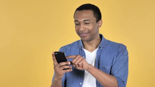 Young Adult Using Smartphone on Yellow Background
