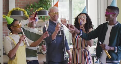 Grupo feliz de diversos amigos em chapéus de festa comemorando juntos, brindando com videira