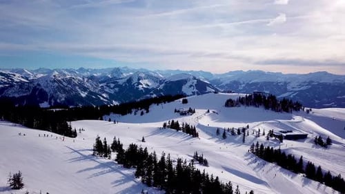 Aerial view smoothement along the ski slopes in the ski resort. Magnificent snowy mountains and blue