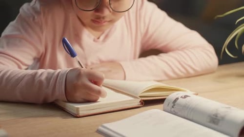 Asiatisches Kind macht nachts Hausaufgaben, asiatisches Kind schreibt auf Buch