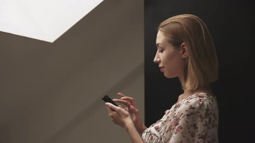 Young Woman in Profile Works on Smartphone