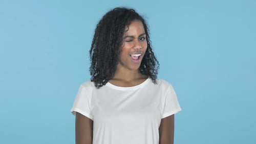 Young Woman Smiling and Winking on Blue Background
