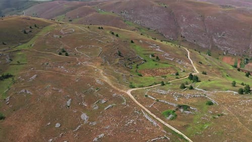 Aerial View of Arid Country Land Some Green Bushes and Trees Blue Sky Mountain in the Horizon Dirty
