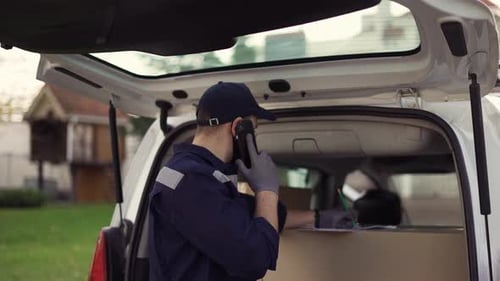 Handsome Delivery Man Checking Delivery List While Talking on the Phone