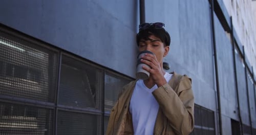 Young Adult Drinks from a Travel Cup in City