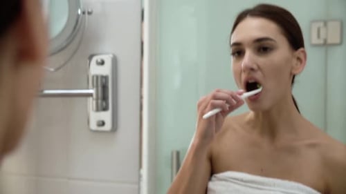 Salud dental. Mujer cepillándose los dientes en el baño