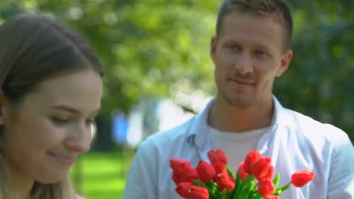 Romantic Couple Exchanging Flowers in Park