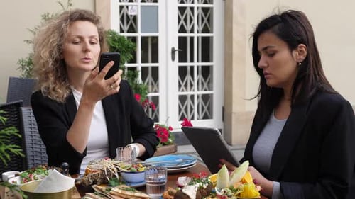 Two Women Using Technology at Restaurant
