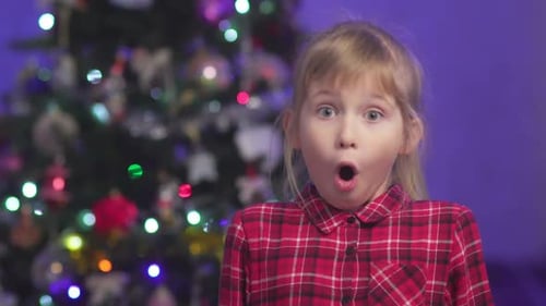 Surprised Young Girl in Front of Christmas Tree