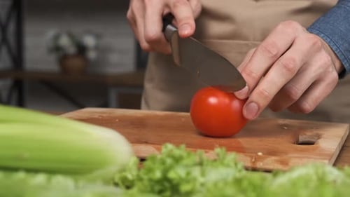 Chef Slices Tomato in Kitchen for Salad
