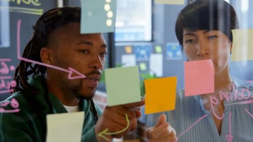 Business executives discussing over sticky note in office 4k