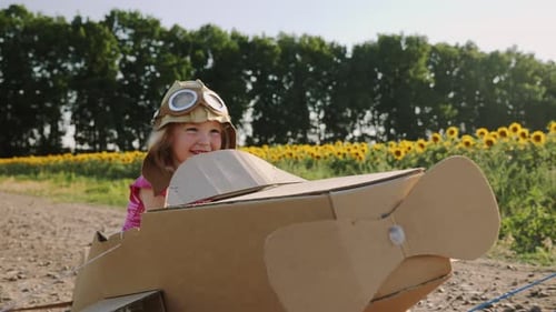 Glückliches kleines Mädchen reitet in einem Kartonflugzeug