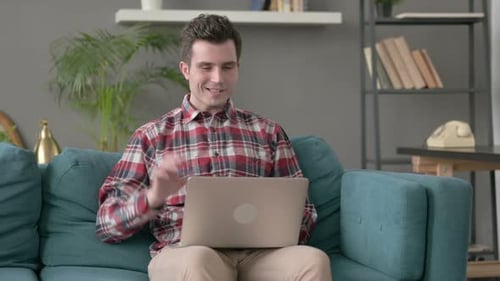 Smiling Man Using Laptop on Blue Couch