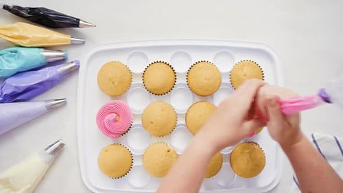 Step by step. Pastry chef piping butter cream frosting on unicorn cupcakes for little girl birthday