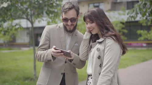 Smiling Couple Looking at Smartphone Together Outside