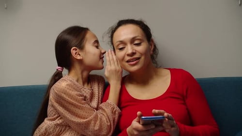 Girl Whispering to Woman Holding Cell Phone