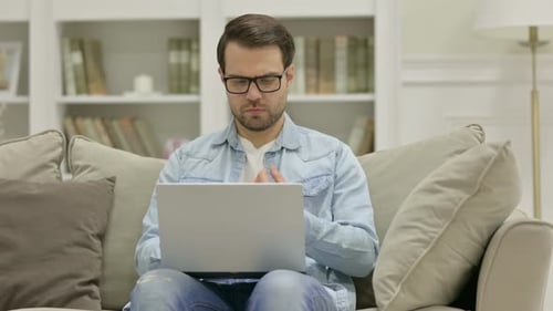 Young Man with Laptop Having Wrist Pain at Home
