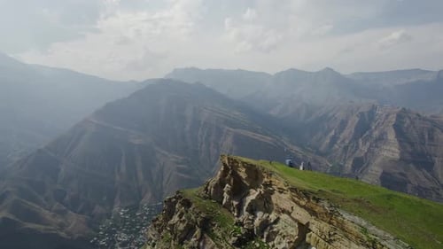 Travelers on rocky cliff on background of high mountains