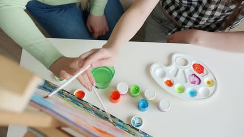 High Angle View of Female Hands Mother and Daughter Painting Picture with Watercolors in Studio