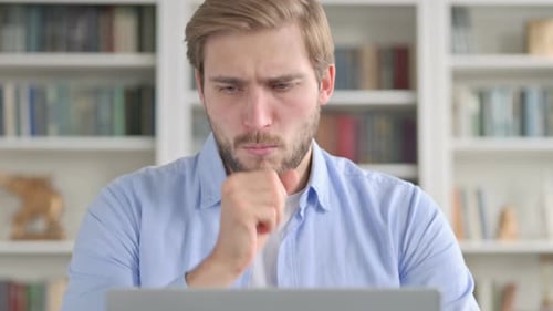 Young Adult Working on Laptop Coughing into Fist