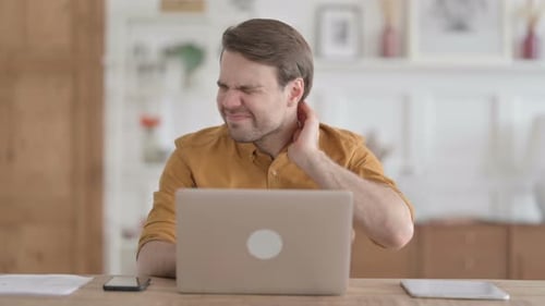 Man Experiencing Neck Pain While Working at Laptop