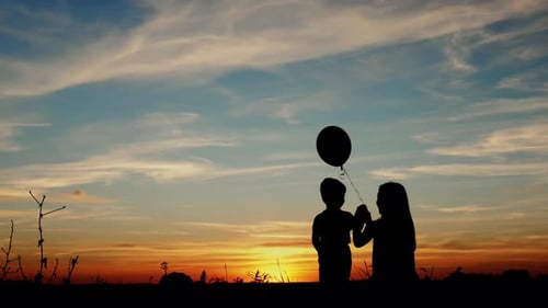 Child and Adult Silhouette with Balloon at Sunset