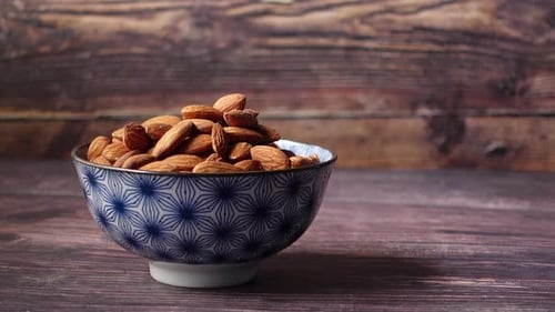 Bowl of Almonds Moved by Hands on Table