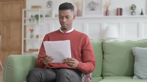 Young Adult Man Reviews Documents on Sofa