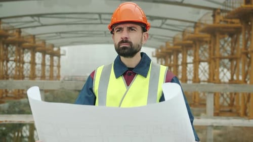Construction Worker Inspecting Building Plans on Site
