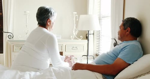 Loving Senior Wife Giving Husband Medicine in Bed