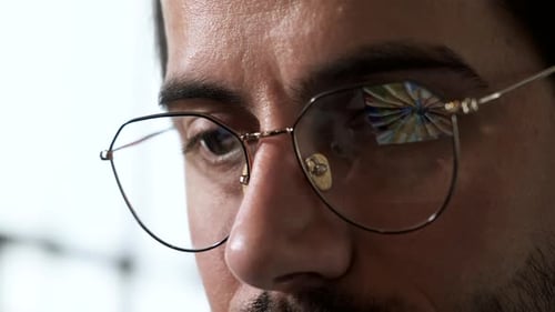 Close-up Portrait of a Young European Man with Glasses, the Reflection of Images is Working