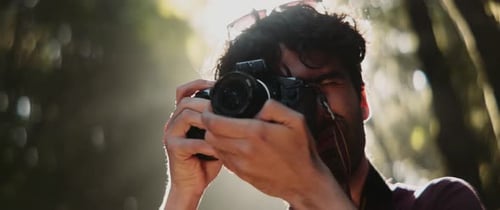 Man focuses and takes photo in forest
