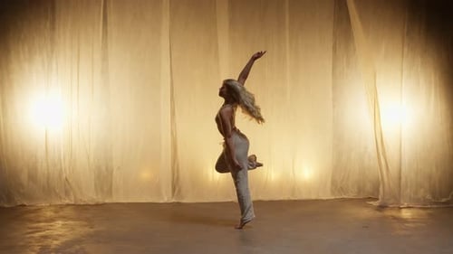 Silhouette of a Professional Dancer Performing in Studio in Soft Warm Lighting