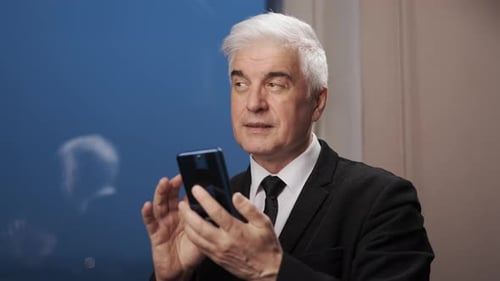Senior Man Using Smartphone in Suit Indoors