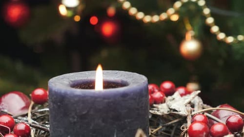 Burning Candle with Christmas Tree in Background
