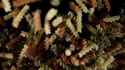 Rotini Pasta Macaroni vole après avoir explosé. Tas de pâtes multicolores Bouncing Black Bg