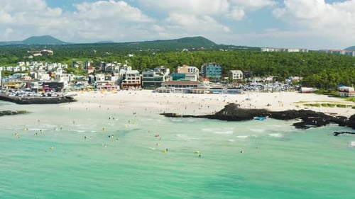 People enjoying summer vacation and wavy beach scenery. Jeju Island.