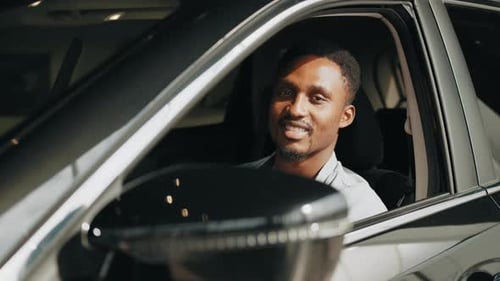 Smiling Man Holding Car Key in New Automobile