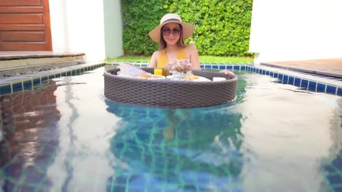 Woman with floating breakfast in pool