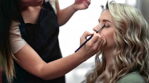 Makeup Artist Applying Eyeshadow to Woman in Salon