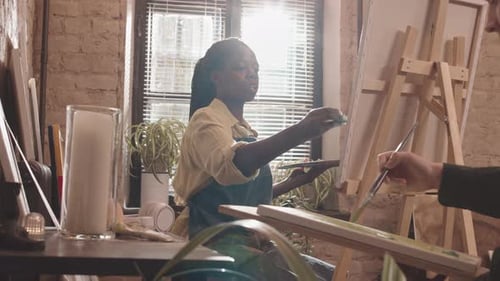 Femme noire peignant dans un studio lumineux