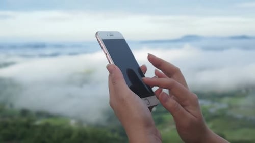 Hands Using Smartphone with Mountainous Background