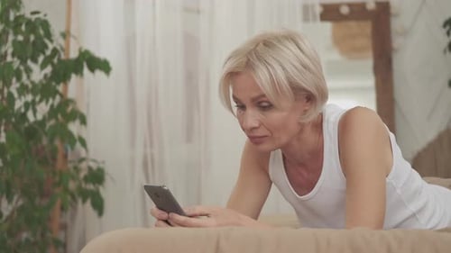 Woman Relaxing in Bed with Smartphone