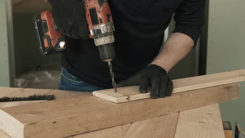 Man Drilling Wood with Power Drill on Workbench