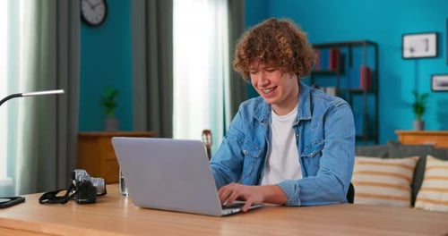 Teen with Curly Hair Works on Laptop at Home