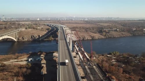 Construction of a bridge across the river. Heavy traffic on the bridge. Drone aerial high angle view