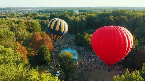 Aerial View of Red Hot Air Balloon Takes Off Among the Trees in the Park. Beautiful Sky and Sunset